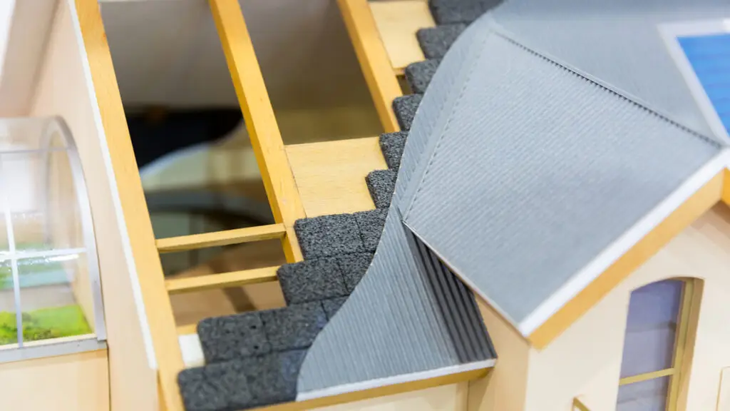 Modell eines Hausdachs mit sichtbarer Holzkonstruktion und mehreren Dämmschichten; Darstellung des typischen Dachaufbaus für energetische Sanierungen.